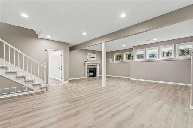 unfurnished living room featuring light hardwood / wood-style floors, a healthy amount of sunlight, and a stone fireplace