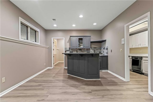 kitchen featuring gray cabinetry, light hardwood / wood-style floors, a center island, and a breakfast bar area