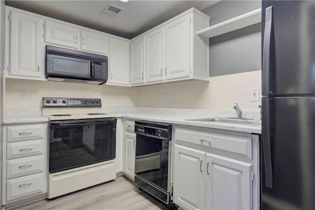 kitchen featuring white cabinets, black appliances, light wood-type flooring, and sink