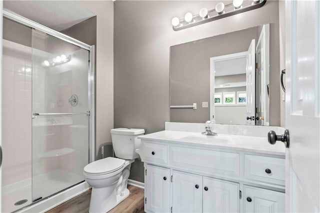 bathroom featuring walk in shower, vanity, toilet, and hardwood / wood-style flooring