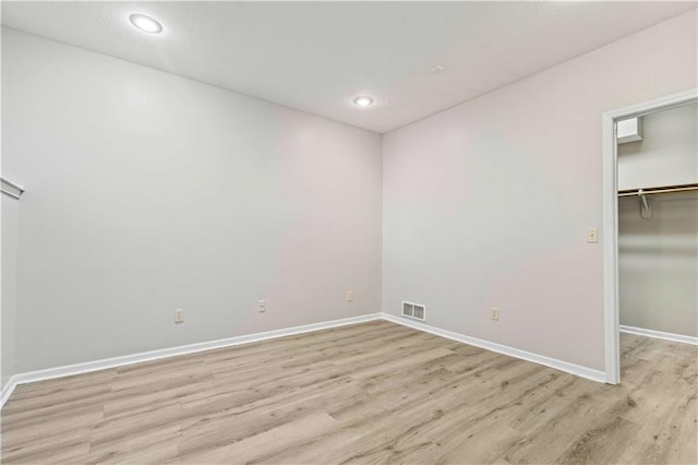 unfurnished bedroom with light hardwood / wood-style flooring, a closet, and a walk in closet