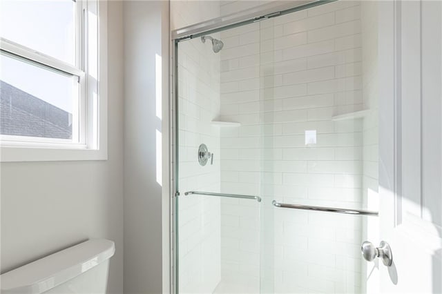 bathroom featuring toilet and an enclosed shower