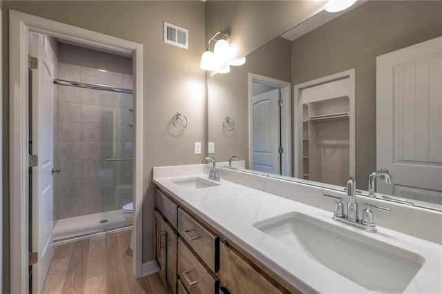 bathroom featuring wood-type flooring, toilet, a shower with door, and vanity