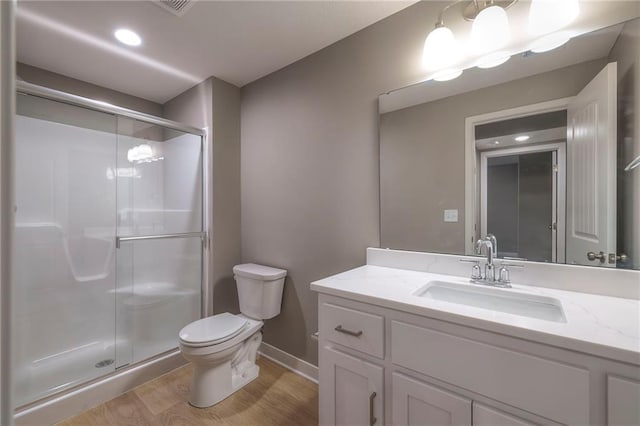 bathroom with a shower with door, vanity, hardwood / wood-style floors, and toilet