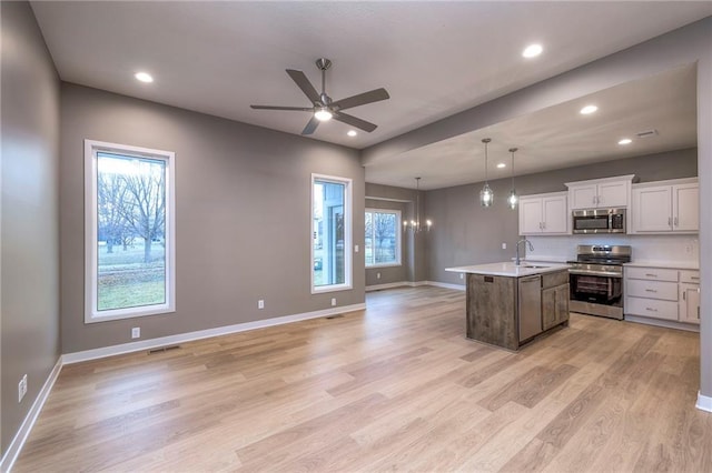 kitchen featuring pendant lighting, sink, appliances with stainless steel finishes, a kitchen island with sink, and white cabinets