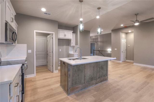 kitchen with sink, hanging light fixtures, a center island with sink, appliances with stainless steel finishes, and white cabinets