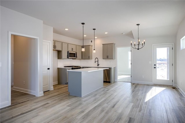 kitchen featuring light wood-type flooring, hanging light fixtures, a center island, and gray cabinets