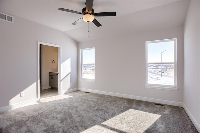 carpeted empty room featuring a healthy amount of sunlight, lofted ceiling, and ceiling fan