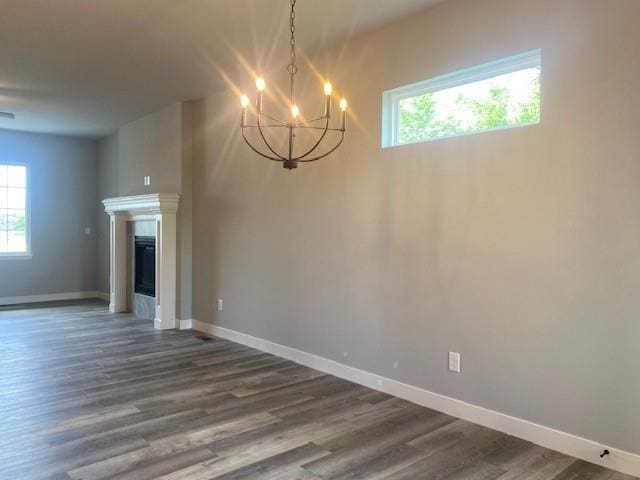 20870 W 190th Ter, Spring Hill, KS 66083 - unfurnished dining area with a chandelier, plenty of natural light, dark wood-style flooring, and a glass covered fireplace