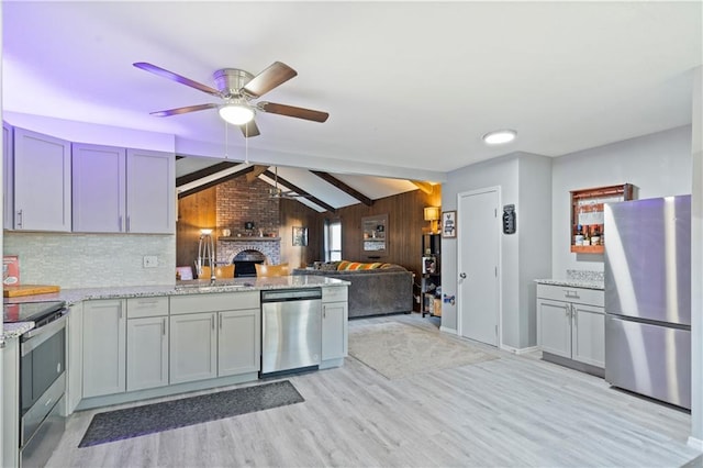 kitchen featuring light hardwood / wood-style flooring, a brick fireplace, appliances with stainless steel finishes, and sink