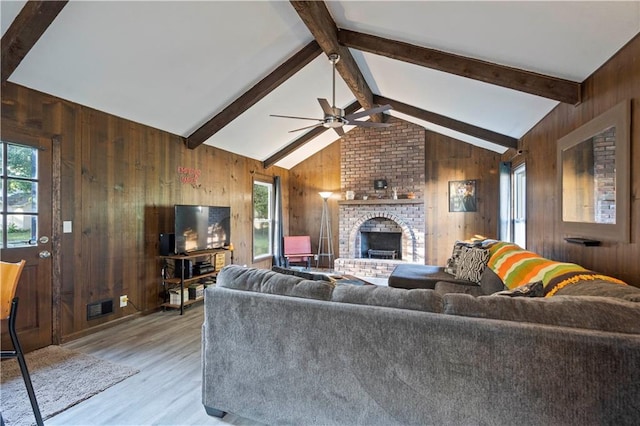 living room featuring a fireplace, light wood-type flooring, wood walls, and a healthy amount of sunlight