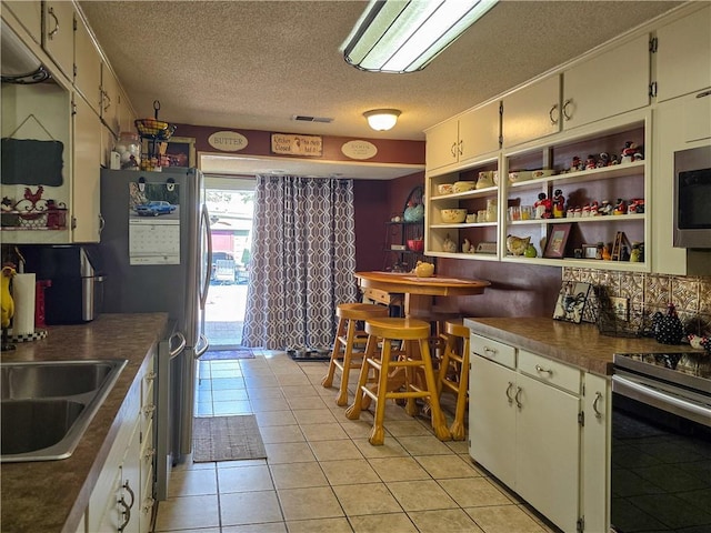 kitchen featuring light tile patterned flooring, appliances with stainless steel finishes, sink, and a textured ceiling