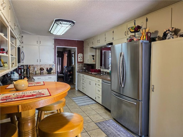 kitchen featuring light tile patterned floors, sink, a textured ceiling, white cabinetry, and stainless steel appliances