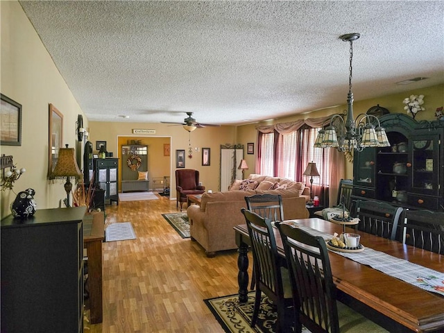 dining space featuring ceiling fan with notable chandelier, light hardwood / wood-style floors, and a textured ceiling