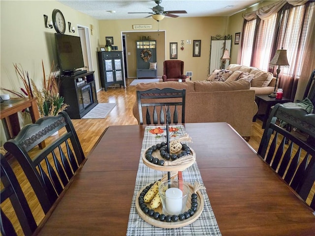 dining area featuring wood-type flooring, a textured ceiling, and ceiling fan