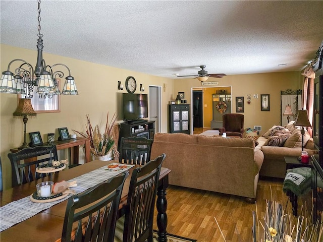 dining room with a textured ceiling, ceiling fan with notable chandelier, and light hardwood / wood-style floors