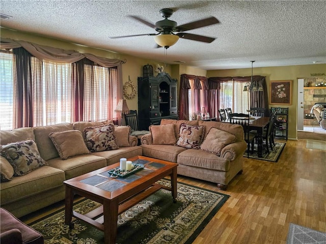 living room featuring light wood-type flooring, a healthy amount of sunlight, a textured ceiling, and ceiling fan