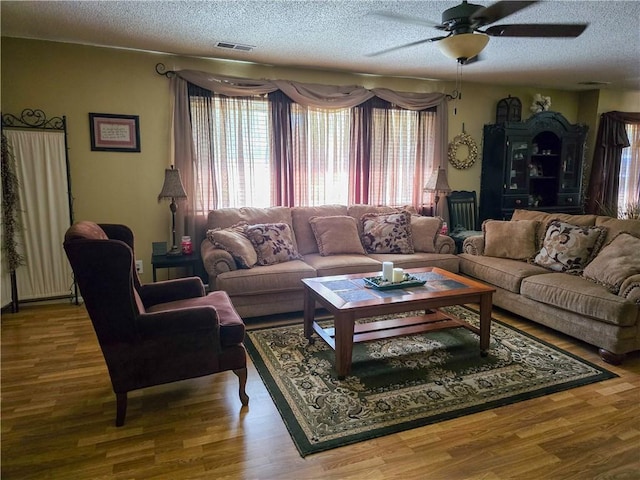 living room featuring ceiling fan, a textured ceiling, and hardwood / wood-style floors