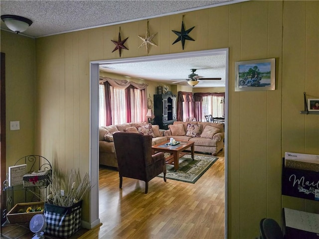 living room featuring wood-type flooring, a textured ceiling, ceiling fan, and a wealth of natural light