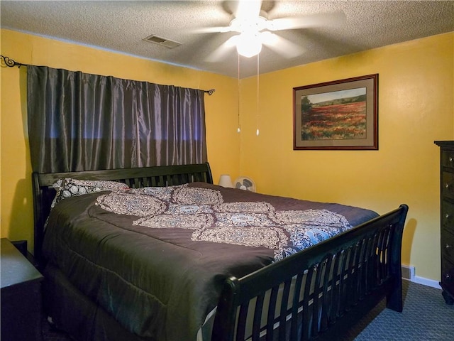 bedroom with ceiling fan, carpet floors, and a textured ceiling