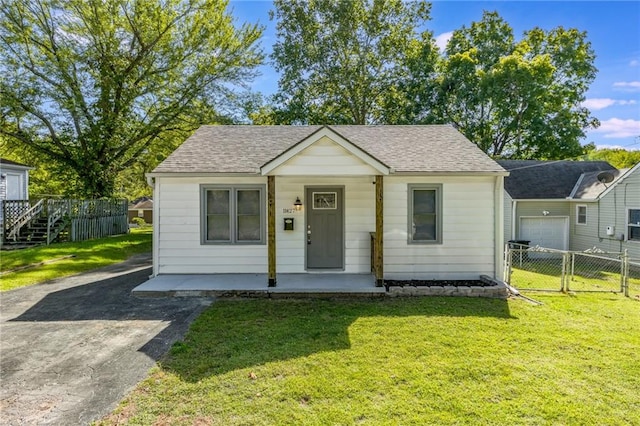 bungalow-style house with covered porch, a garage, and a front lawn