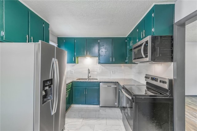 kitchen with appliances with stainless steel finishes, decorative backsplash, sink, and a textured ceiling