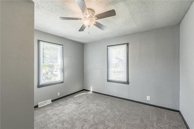 carpeted spare room with a textured ceiling, a healthy amount of sunlight, and ceiling fan