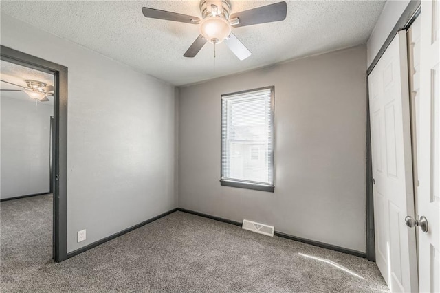 unfurnished bedroom featuring carpet, a textured ceiling, and ceiling fan