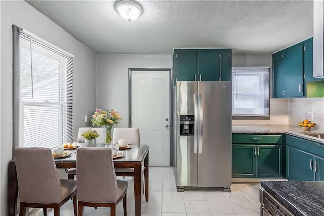 kitchen featuring decorative backsplash, stainless steel fridge, a textured ceiling, and dark stone counters