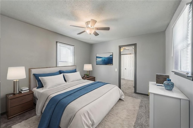 carpeted bedroom with ceiling fan, a textured ceiling, and multiple windows