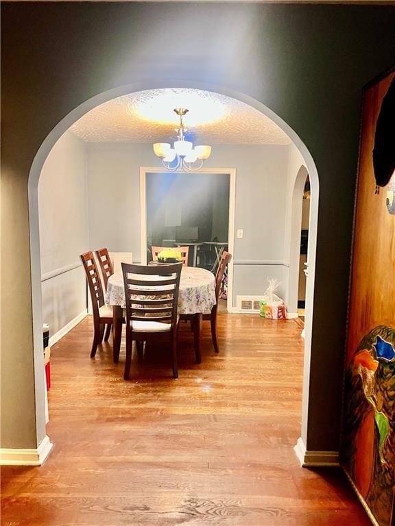 dining room with a chandelier, wood-type flooring, and a textured ceiling