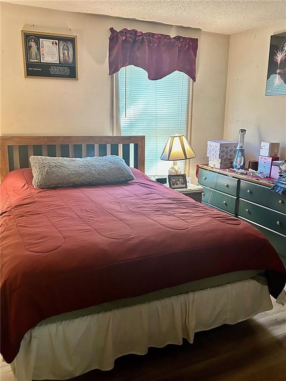 bedroom with a textured ceiling and wood-type flooring