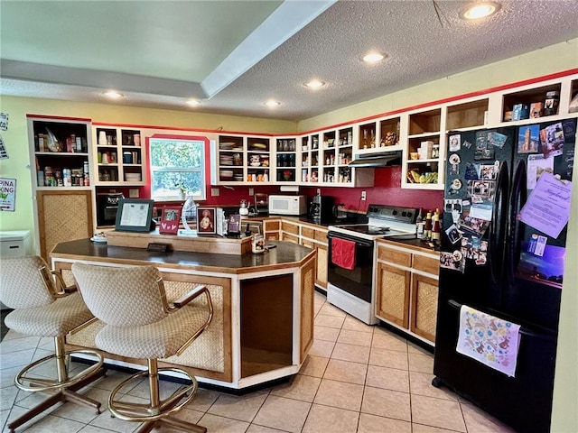 kitchen with built in desk, a textured ceiling, white appliances, a center island with sink, and light tile patterned floors