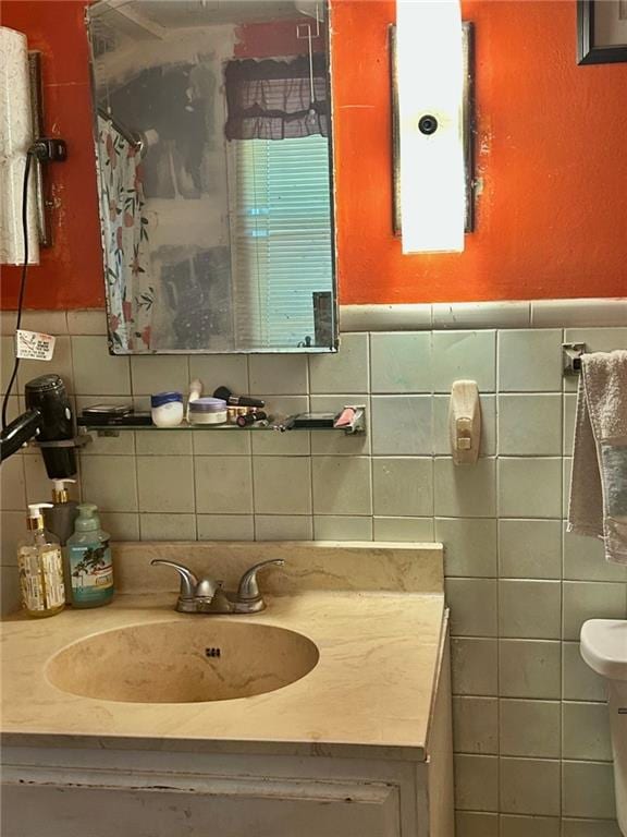 bathroom with walk in shower, vanity, tile walls, and toilet