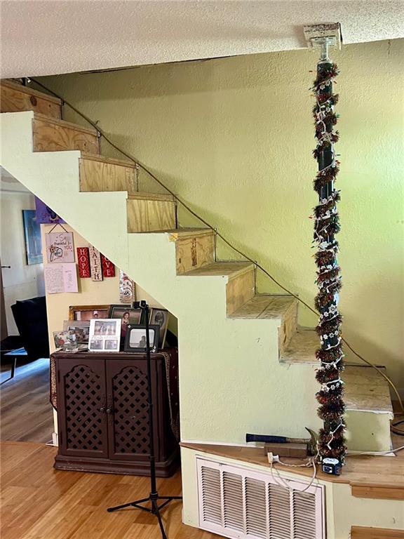 staircase featuring a textured ceiling and wood-type flooring