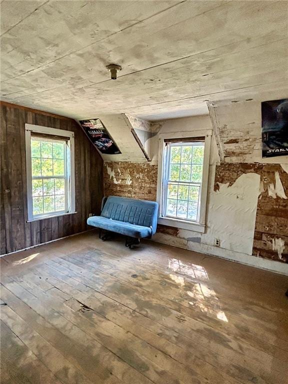 unfurnished bedroom featuring wooden walls, hardwood / wood-style floors, and multiple windows