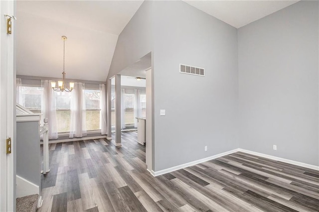 interior space featuring ceiling fan with notable chandelier, dark hardwood / wood-style flooring, and vaulted ceiling