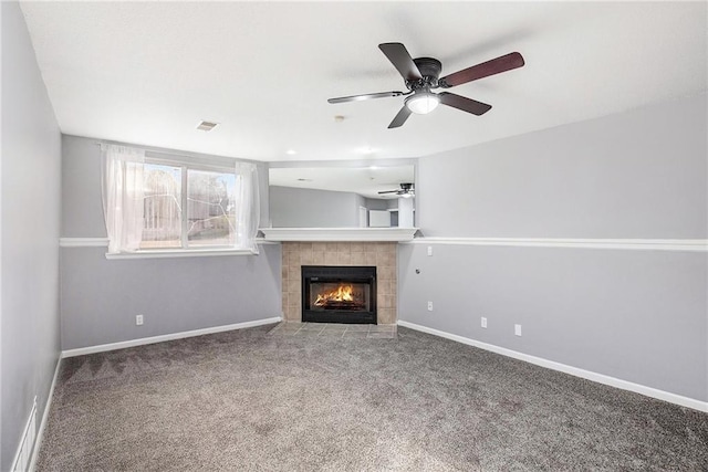 unfurnished living room with carpet, ceiling fan, and a tiled fireplace