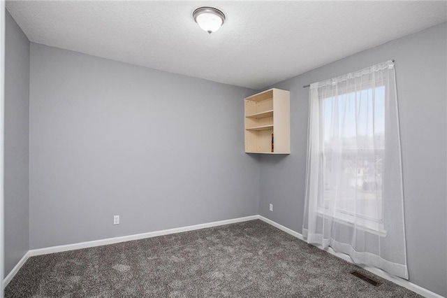 carpeted empty room with a textured ceiling