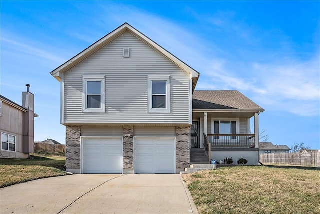 split level home with covered porch, a garage, and a front yard