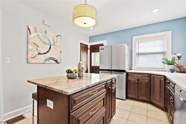 507 E 75th St, Kansas City, MO 64131 - kitchen featuring dark brown cabinetry, light tile patterned floors, stainless steel appliances, a kitchen island, and visible vents