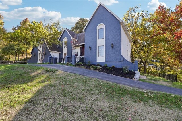 traditional home featuring brick siding, fence, and a front yard