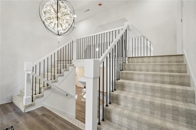 stairway with a chandelier, baseboards, and wood finished floors