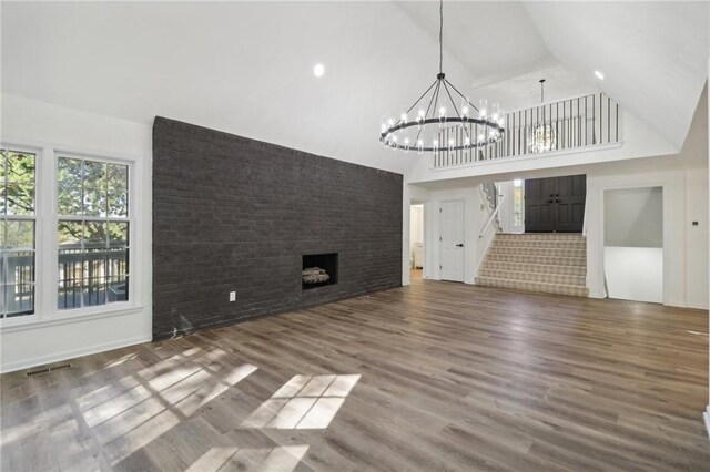 unfurnished living room featuring an inviting chandelier, high vaulted ceiling, and dark hardwood / wood-style flooring