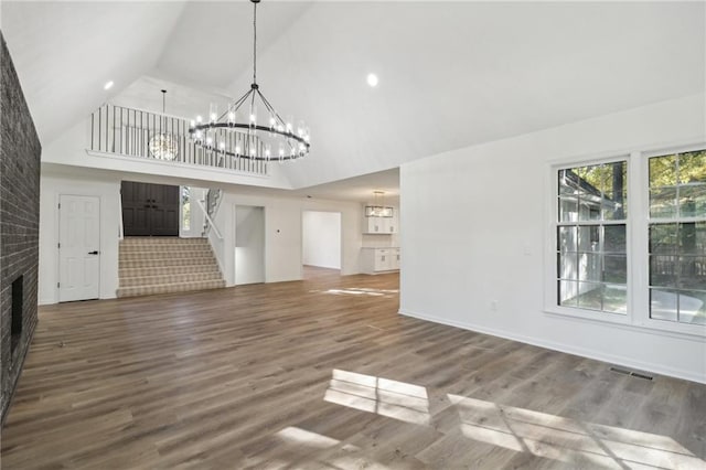 unfurnished living room with hardwood / wood-style flooring, high vaulted ceiling, a chandelier, and a brick fireplace