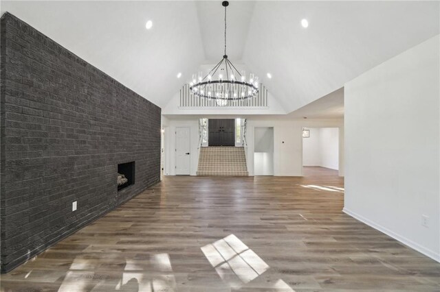 unfurnished living room with high vaulted ceiling, brick wall, a fireplace, and hardwood / wood-style floors