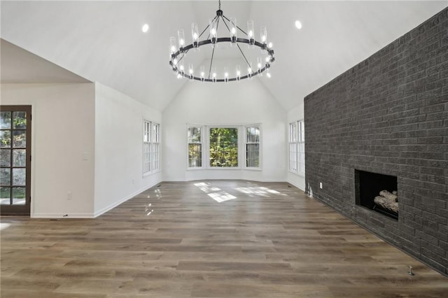 unfurnished living room with hardwood / wood-style flooring, high vaulted ceiling, plenty of natural light, and a brick fireplace