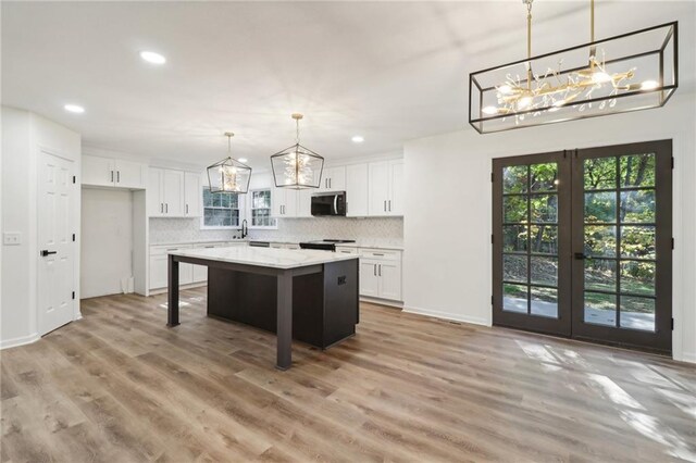 kitchen featuring pendant lighting, white cabinetry, light wood-type flooring, and a kitchen island