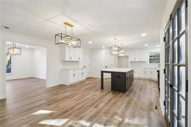 kitchen with a kitchen island, white cabinetry, light hardwood / wood-style floors, and plenty of natural light