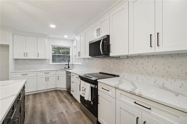 kitchen featuring light stone countertops, stainless steel appliances, light wood finished floors, a sink, and white cabinetry